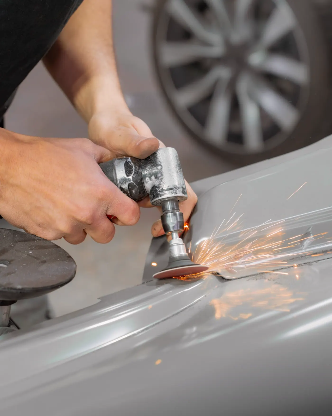 Ponçage d'une tole avec gerbe d'etincelles en carrosserie