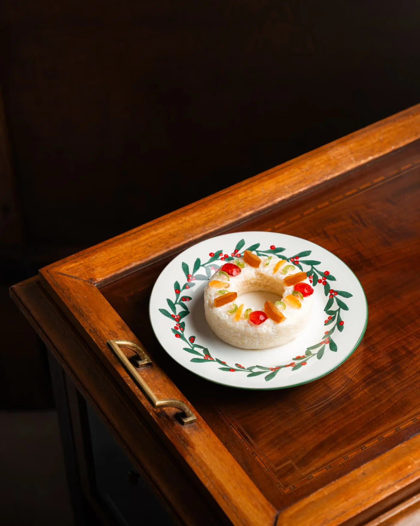 Dessert de fin d'année aux fruits confits présenté sur une assiette décorée, posée sur un meuble en bois