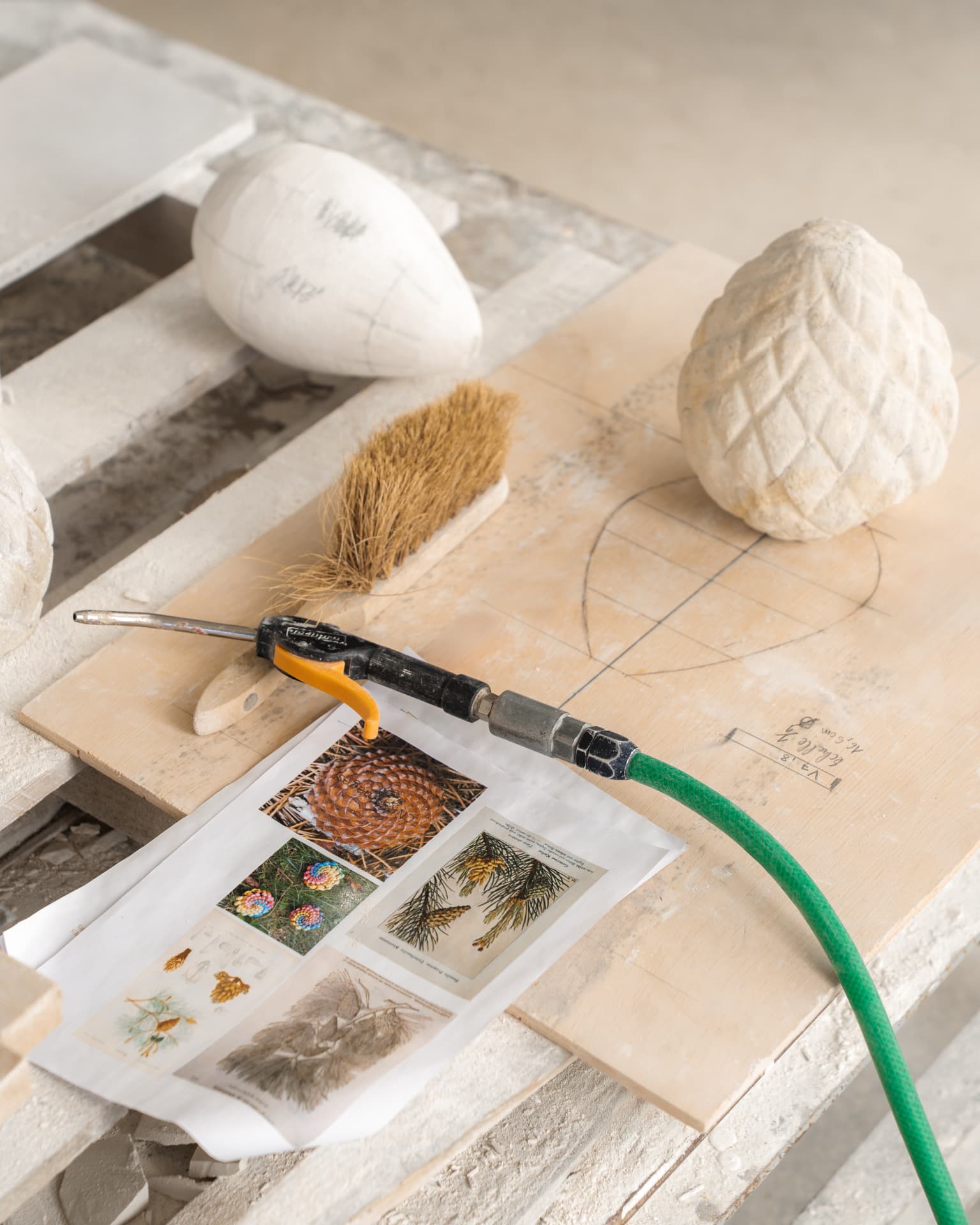 Outils et gabarits posés sur un plan de travail d'atelier, pièces de pierre sculptées et document de référence