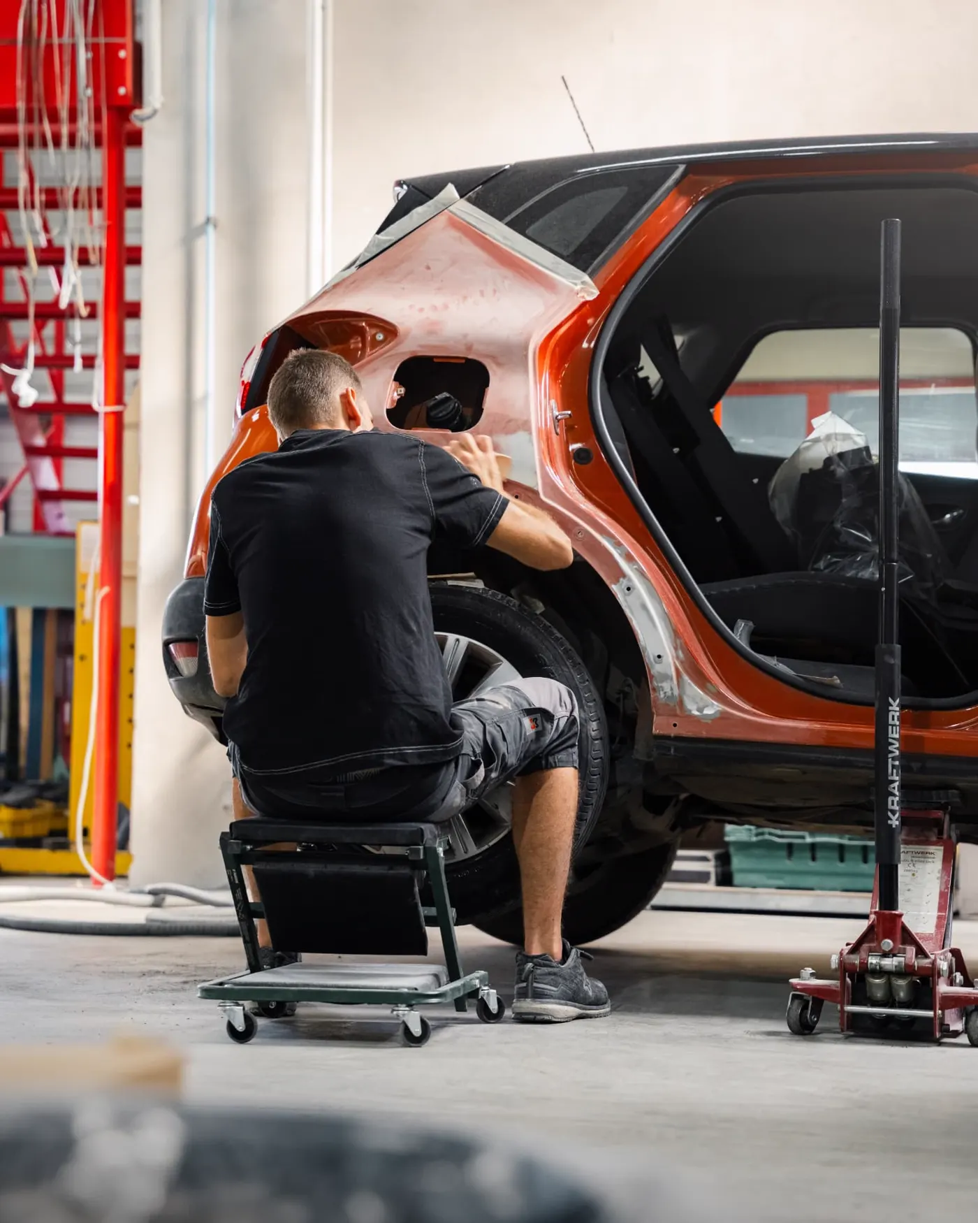 Carrossier travaillant sur l'aile arriere d'un Captur orange