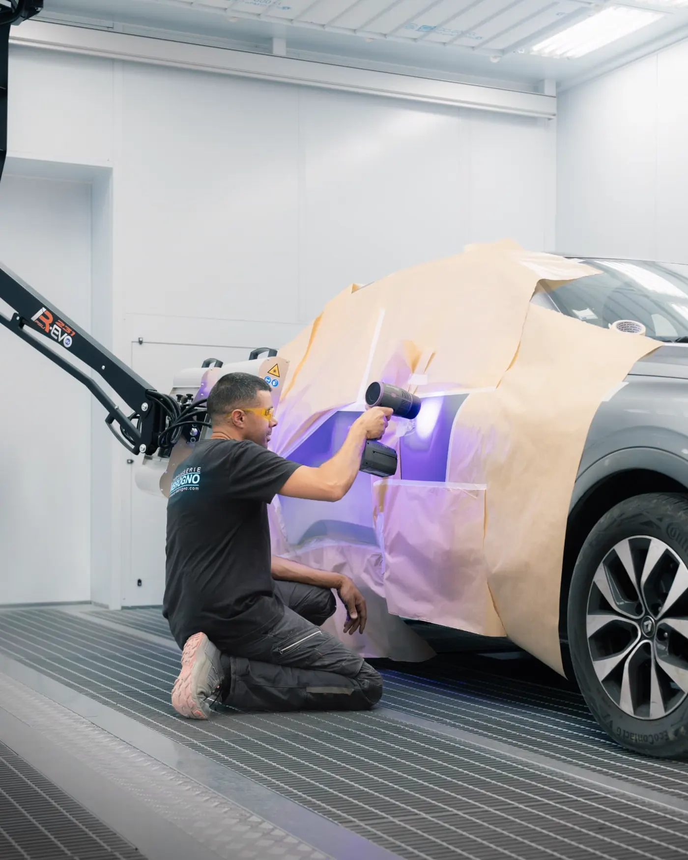 Peinture d'un vehicule sous lampe UV dans une cabine de carrosserie