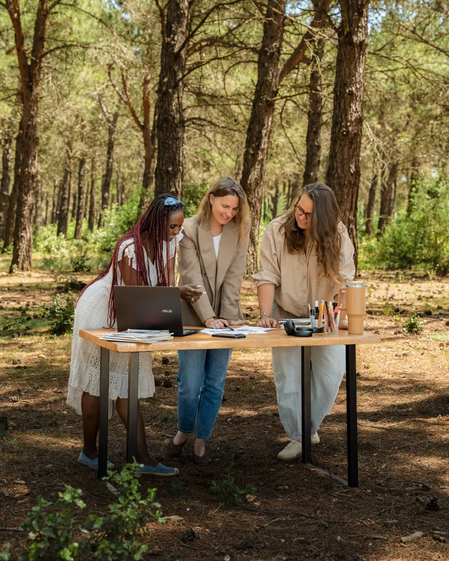 Trois membres de l'équipe BICPOM pr éparent un planning éditorial autour d'une table installée dans une pinède en Provence